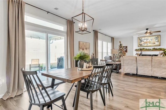 dining area featuring ceiling fan with notable chandelier and light wood-type flooring