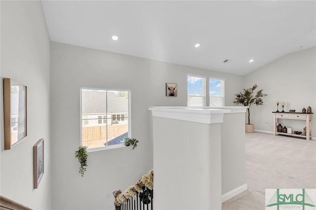 corridor featuring a wealth of natural light, light colored carpet, and vaulted ceiling