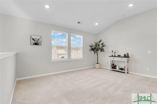 interior space with light carpet and vaulted ceiling