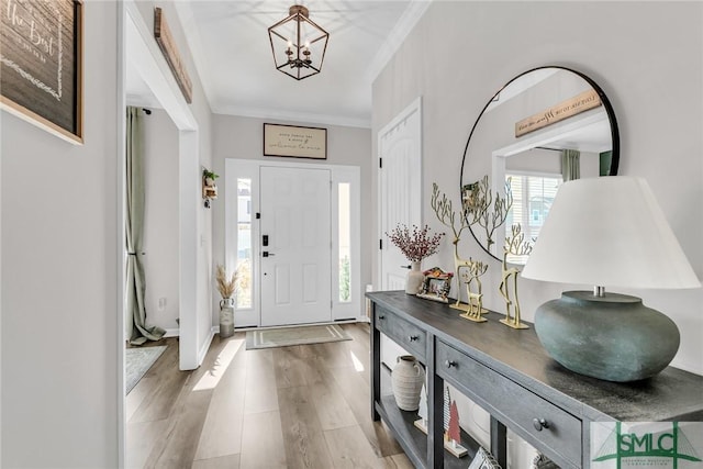 foyer entrance with hardwood / wood-style flooring, crown molding, and an inviting chandelier