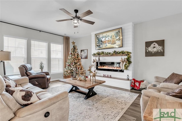 living room with ceiling fan, wood-type flooring, and a fireplace