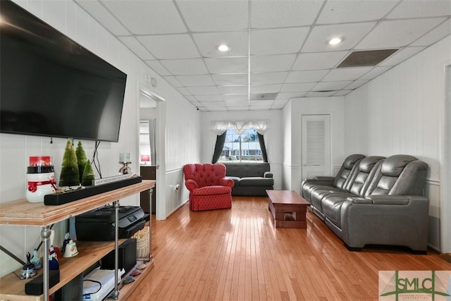 living room with a paneled ceiling and light hardwood / wood-style floors