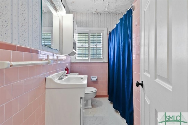 bathroom featuring toilet, vanity, tile patterned floors, and tile walls