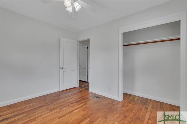 unfurnished bedroom featuring hardwood / wood-style flooring, ceiling fan, and a closet