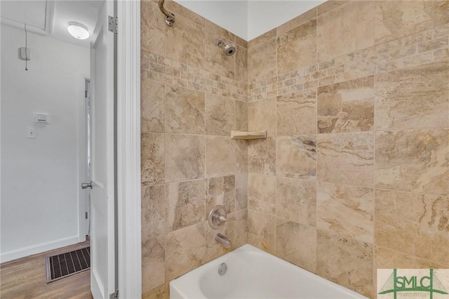 bathroom with hardwood / wood-style flooring and tiled shower / bath