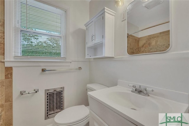 bathroom with vanity, heating unit, and toilet