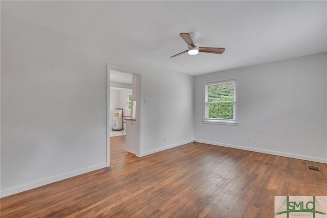 spare room with electric water heater, ceiling fan, and wood-type flooring