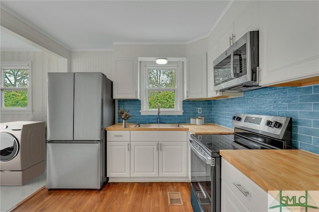 kitchen featuring wood counters, sink, washer / dryer, white cabinetry, and stainless steel appliances