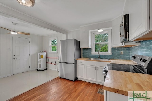 kitchen with sink, water heater, wooden counters, white cabinets, and appliances with stainless steel finishes