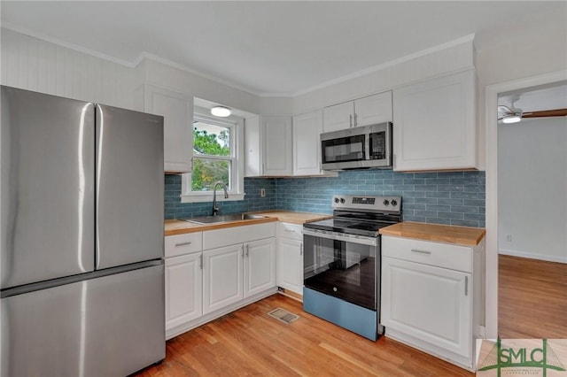 kitchen featuring sink, light hardwood / wood-style flooring, butcher block countertops, white cabinetry, and stainless steel appliances