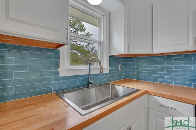 kitchen with white cabinets, a healthy amount of sunlight, sink, and wooden counters