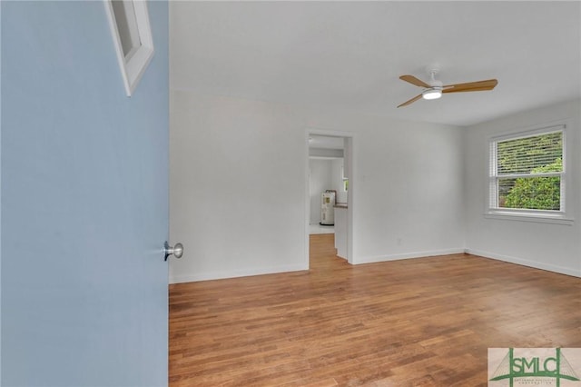 empty room featuring electric water heater, ceiling fan, and light wood-type flooring