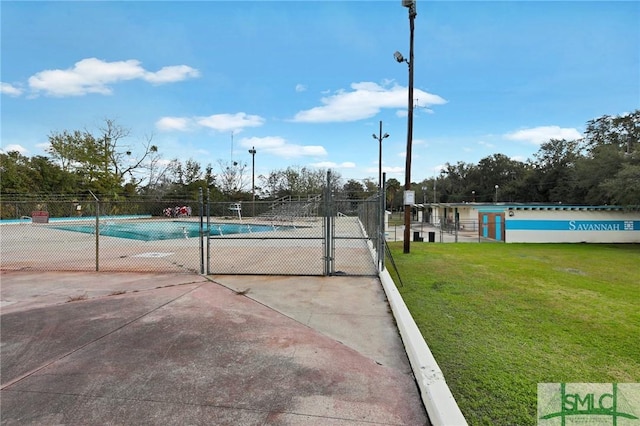 view of swimming pool with tennis court and a yard