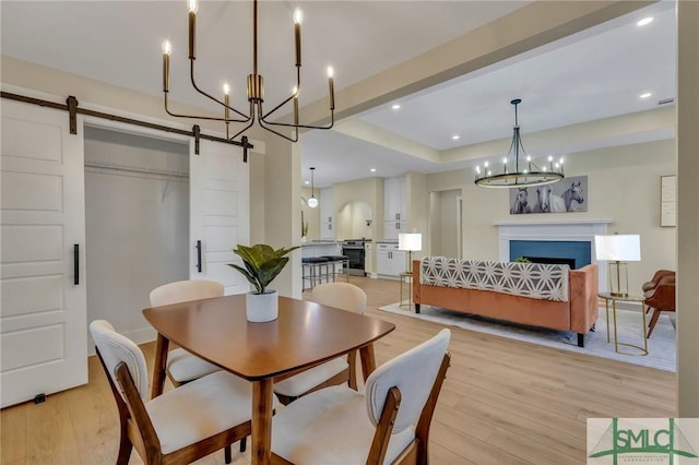 dining room with light wood finished floors, a fireplace, a barn door, a chandelier, and recessed lighting