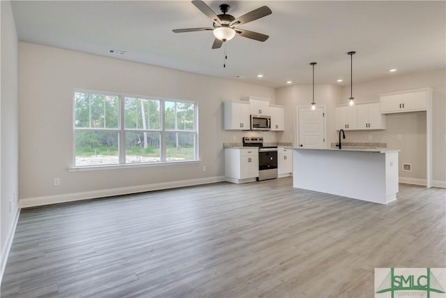 kitchen with appliances with stainless steel finishes, a kitchen island with sink, pendant lighting, light hardwood / wood-style flooring, and white cabinetry