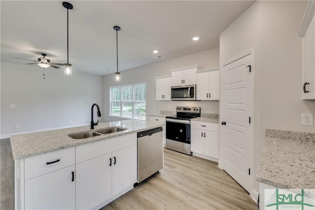 kitchen with a center island with sink, decorative light fixtures, sink, and appliances with stainless steel finishes