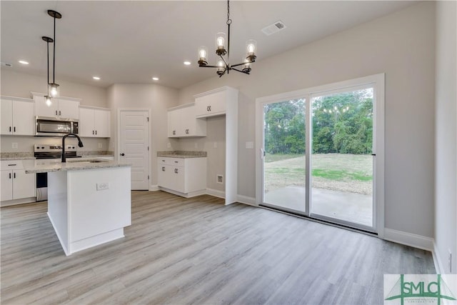 kitchen featuring white cabinetry, hanging light fixtures, stainless steel appliances, a center island with sink, and light wood-type flooring