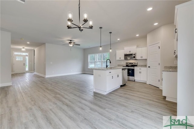 kitchen featuring sink, hanging light fixtures, a center island with sink, white cabinets, and appliances with stainless steel finishes