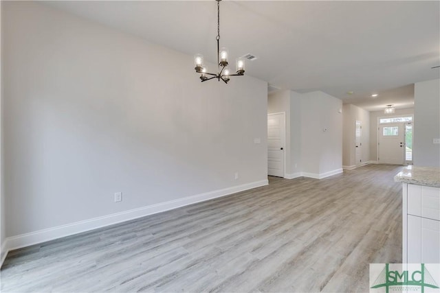 unfurnished living room with a notable chandelier and light wood-type flooring