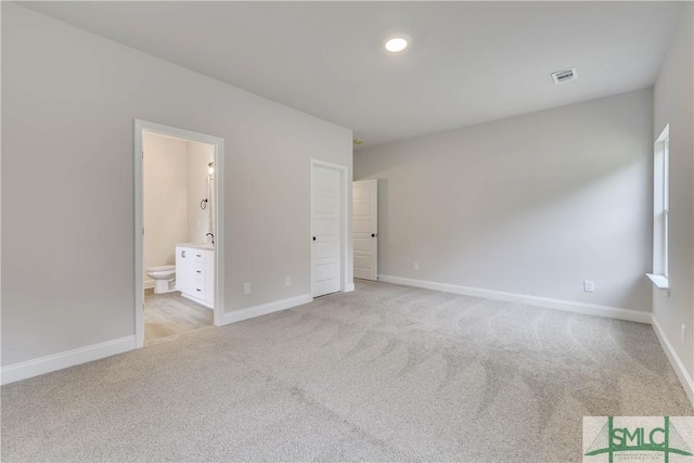 unfurnished bedroom featuring light colored carpet and connected bathroom