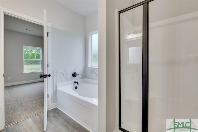 bathroom featuring plus walk in shower and hardwood / wood-style flooring