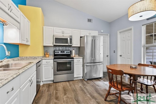 kitchen featuring sink, white cabinets, lofted ceiling, and appliances with stainless steel finishes