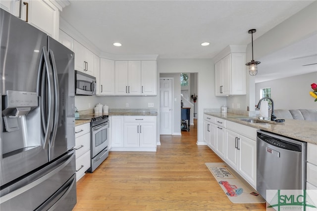 kitchen with white cabinets, sink, hanging light fixtures, light wood-type flooring, and stainless steel appliances