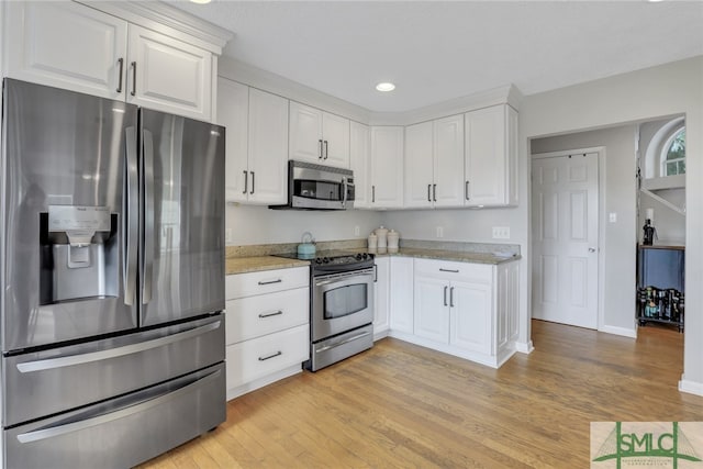 kitchen with white cabinets, light hardwood / wood-style floors, light stone countertops, and appliances with stainless steel finishes