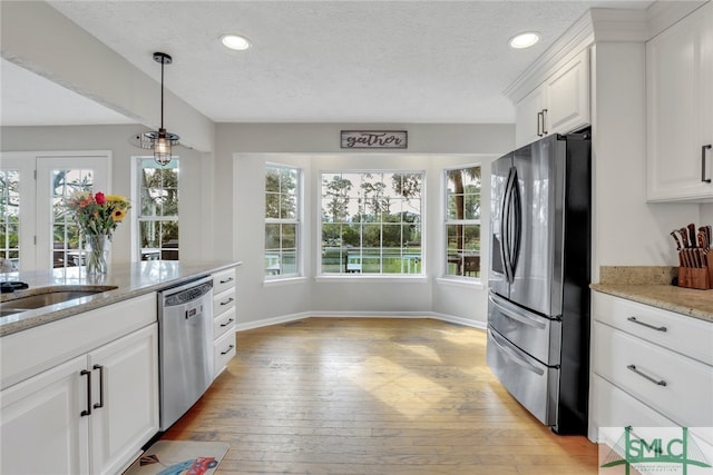 kitchen featuring a wealth of natural light, light wood-type flooring, white cabinetry, and appliances with stainless steel finishes