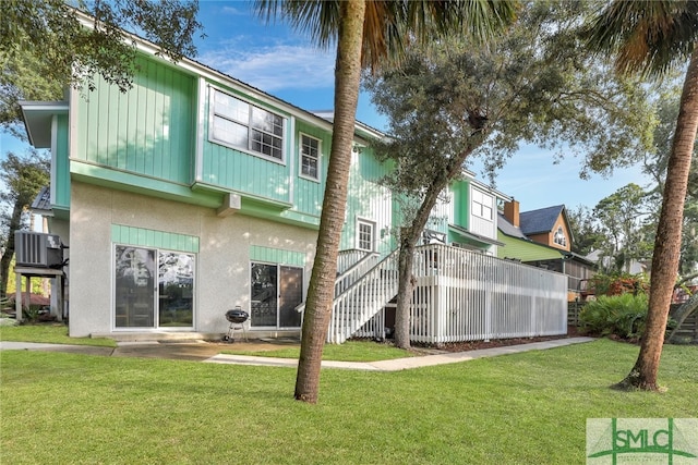 rear view of property featuring central air condition unit and a lawn