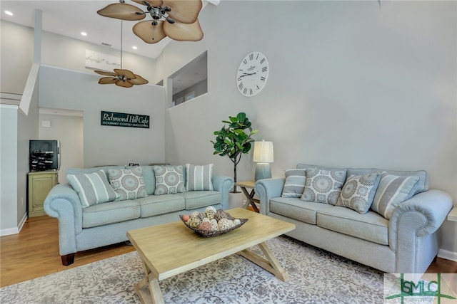 living room with hardwood / wood-style floors, ceiling fan, and a towering ceiling