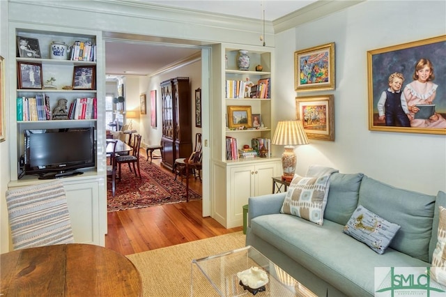 sitting room featuring light wood-type flooring, built in features, and ornamental molding