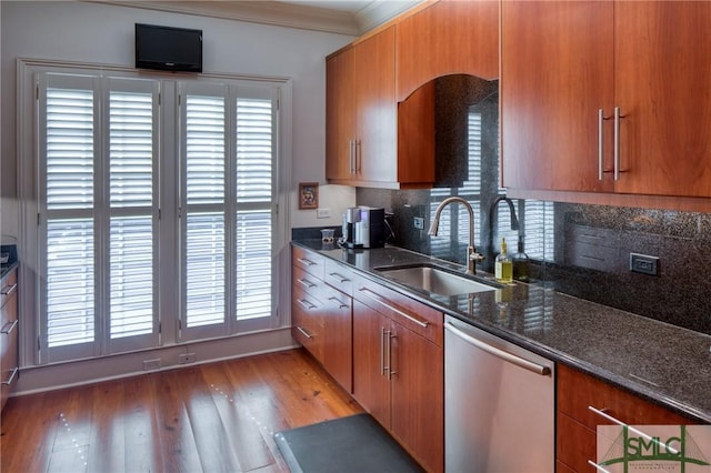 kitchen with tasteful backsplash, stainless steel dishwasher, ornamental molding, dark stone counters, and sink