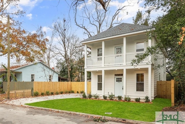 view of front of house featuring a balcony and a front lawn