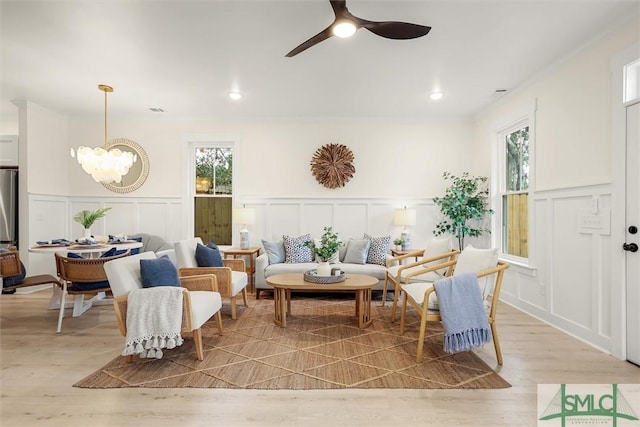 sitting room featuring ceiling fan with notable chandelier and light wood-type flooring