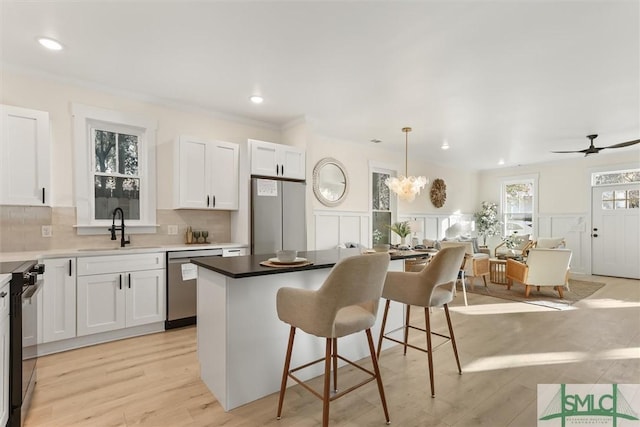 kitchen with white cabinetry, stainless steel dishwasher, hanging light fixtures, and sink