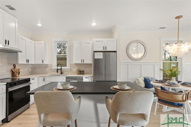 kitchen featuring pendant lighting, white cabinets, a kitchen breakfast bar, sink, and stainless steel appliances