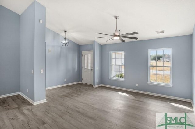 unfurnished living room with ceiling fan with notable chandelier and wood-type flooring