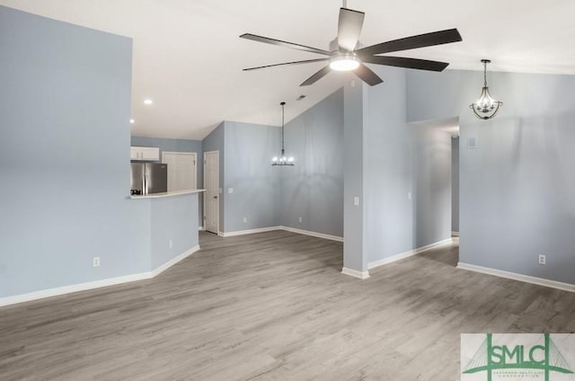 unfurnished living room featuring hardwood / wood-style floors, ceiling fan with notable chandelier, and vaulted ceiling