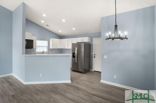 kitchen featuring hardwood / wood-style floors, white cabinets, stainless steel refrigerator with ice dispenser, hanging light fixtures, and kitchen peninsula