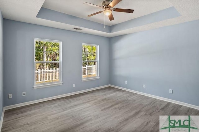 unfurnished room with hardwood / wood-style flooring, ceiling fan, and a tray ceiling