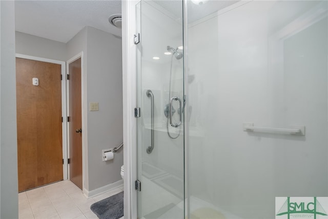 bathroom with toilet, tile patterned floors, and a shower with door