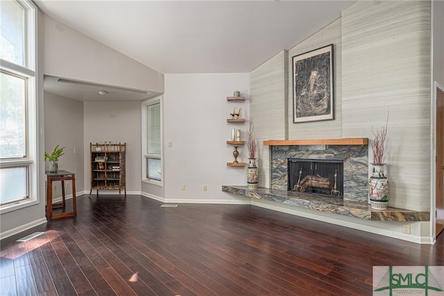 living room with hardwood / wood-style flooring, high vaulted ceiling, a stone fireplace, and a wealth of natural light