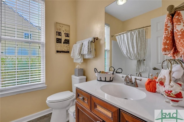 bathroom with tile patterned floors, vanity, toilet, and a wealth of natural light