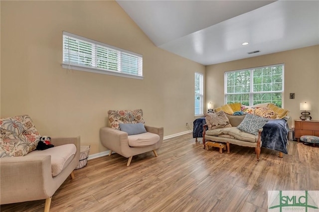 sitting room featuring lofted ceiling, light hardwood / wood-style floors, and a healthy amount of sunlight