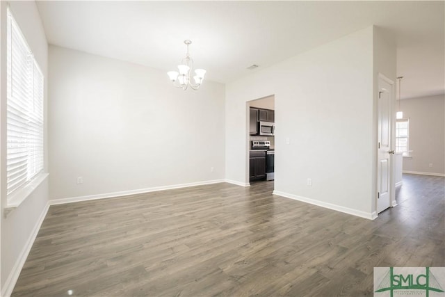 unfurnished living room with dark hardwood / wood-style floors and a chandelier