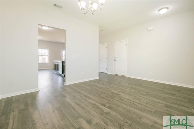 spare room with dark hardwood / wood-style flooring and a notable chandelier