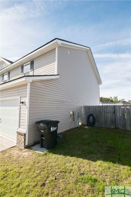 view of side of property featuring a garage and a yard