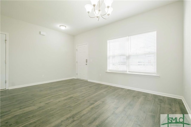 unfurnished room with a chandelier and dark hardwood / wood-style floors