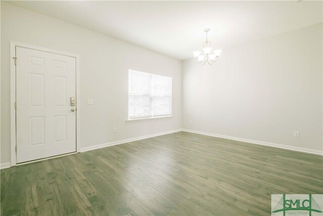 empty room with dark hardwood / wood-style flooring and an inviting chandelier